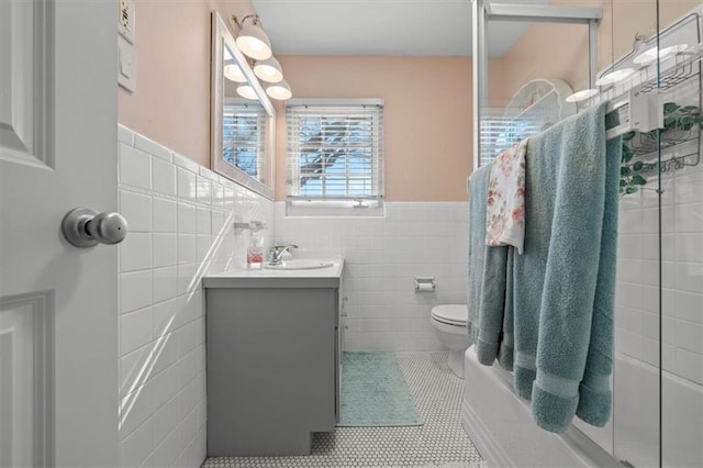 full bathroom featuring toilet, a wainscoted wall, tile patterned flooring, vanity, and tile walls