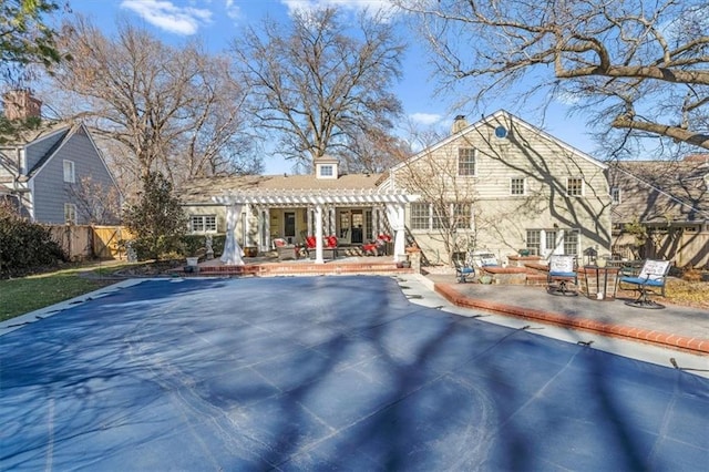 rear view of property featuring a patio, a chimney, fence, and a pergola