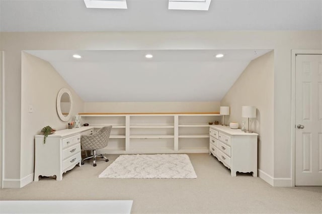 office area featuring light carpet, lofted ceiling with skylight, and baseboards