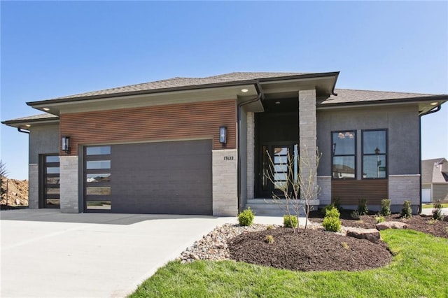 view of front of house featuring roof with shingles, stucco siding, a garage, stone siding, and driveway