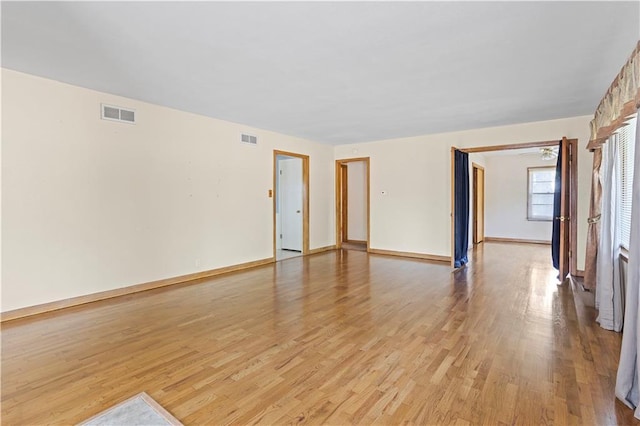 unfurnished room featuring baseboards, visible vents, and light wood finished floors