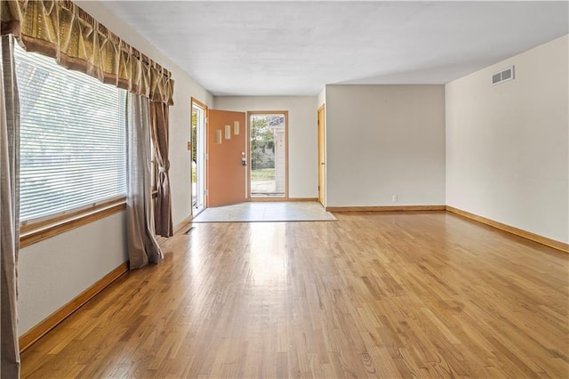 interior space featuring visible vents, light wood-style flooring, and baseboards