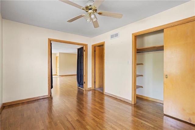 unfurnished bedroom featuring a closet, wood finished floors, visible vents, and baseboards