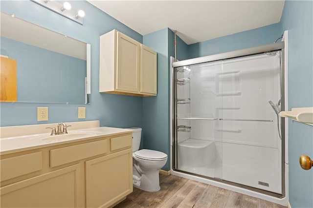 bathroom featuring a stall shower, vanity, toilet, and wood finished floors