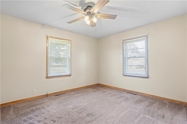 empty room featuring carpet, visible vents, plenty of natural light, and baseboards