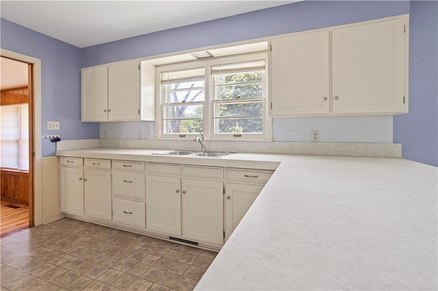 kitchen featuring visible vents, white cabinetry, light countertops, and a sink