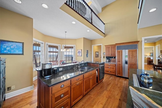 kitchen featuring a sink, dishwasher, light wood-type flooring, paneled built in fridge, and a kitchen island with sink