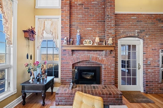 living area with wood finished floors, plenty of natural light, a fireplace, and baseboards