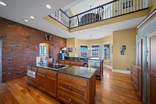 kitchen with light wood finished floors, dishwasher, brick wall, and brown cabinetry