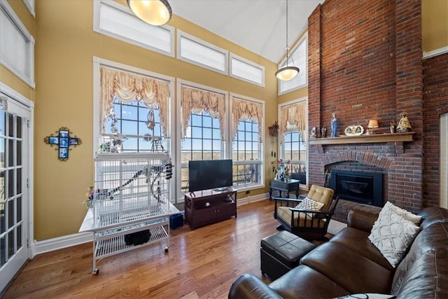 living area with a fireplace, a high ceiling, wood finished floors, and baseboards