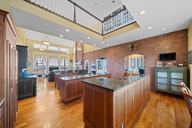 kitchen featuring a large island, a high ceiling, light wood-style floors, and open floor plan