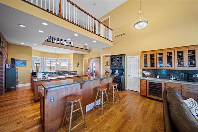 bar featuring indoor wet bar, wine cooler, backsplash, and wood finished floors