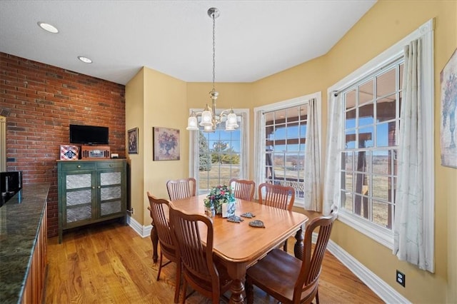 dining space featuring an inviting chandelier, a wood stove, light wood-style floors, and baseboards