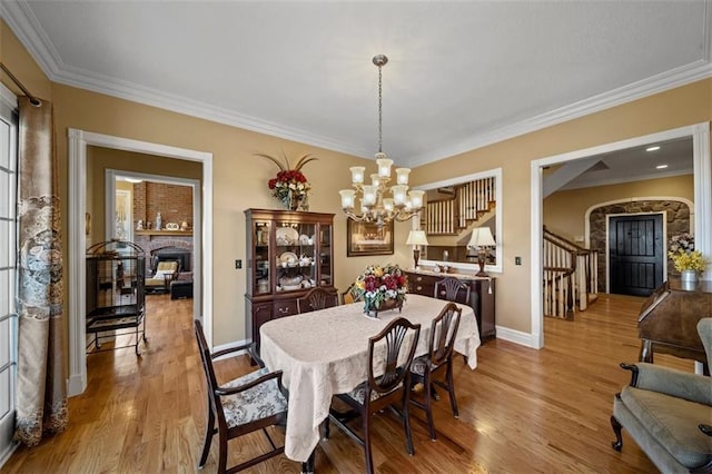 dining room featuring baseboards, stairway, ornamental molding, an inviting chandelier, and wood finished floors