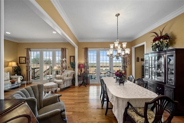 dining area with french doors, plenty of natural light, wood finished floors, and ornamental molding