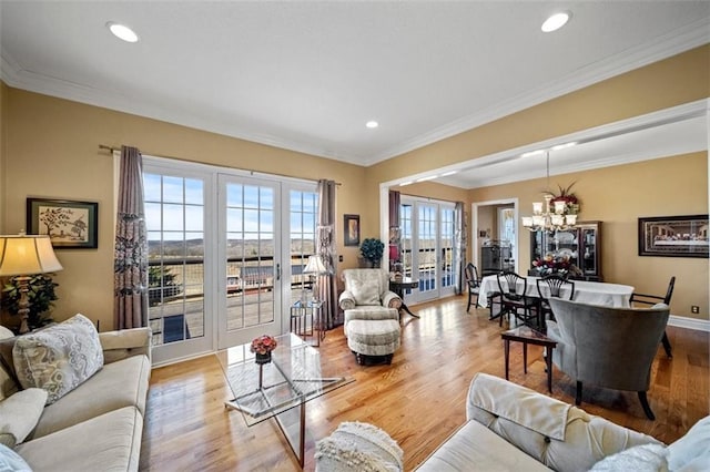 living room featuring recessed lighting, ornamental molding, an inviting chandelier, and wood finished floors