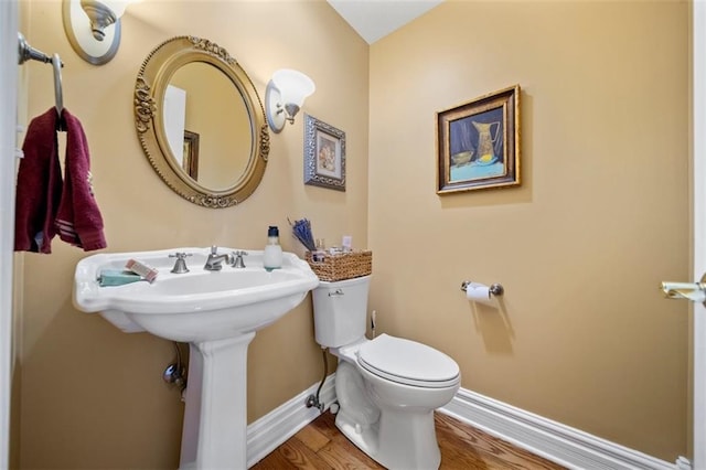 bathroom with toilet, baseboards, and wood finished floors