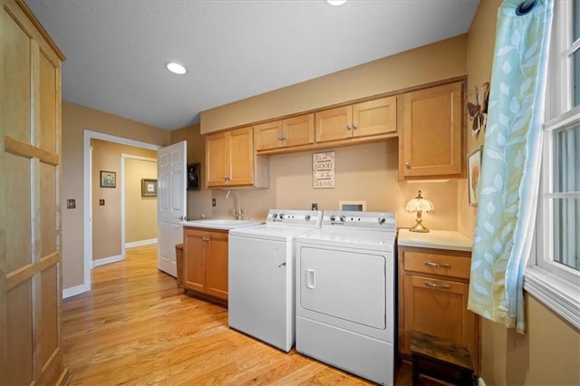 laundry room with light wood-type flooring, a sink, cabinet space, separate washer and dryer, and baseboards