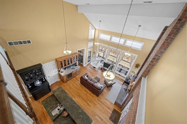 living area featuring visible vents, high vaulted ceiling, beamed ceiling, and wood finished floors