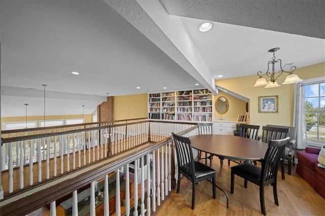 dining area with recessed lighting, a textured ceiling, an inviting chandelier, and wood finished floors