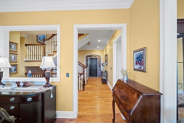 corridor with baseboards, crown molding, stairs, and light wood finished floors