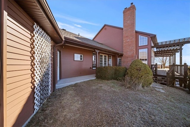 rear view of property featuring a pergola and a chimney