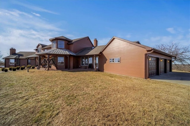 exterior space with a standing seam roof, a chimney, a front lawn, concrete driveway, and a garage