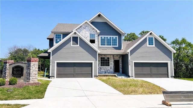 view of front of property with stone siding, an attached garage, and driveway