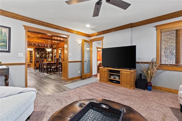 living area featuring a ceiling fan, carpet, baseboards, and crown molding