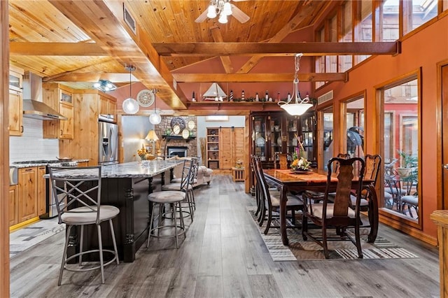 dining space with vaulted ceiling with beams, wood finished floors, and wood ceiling