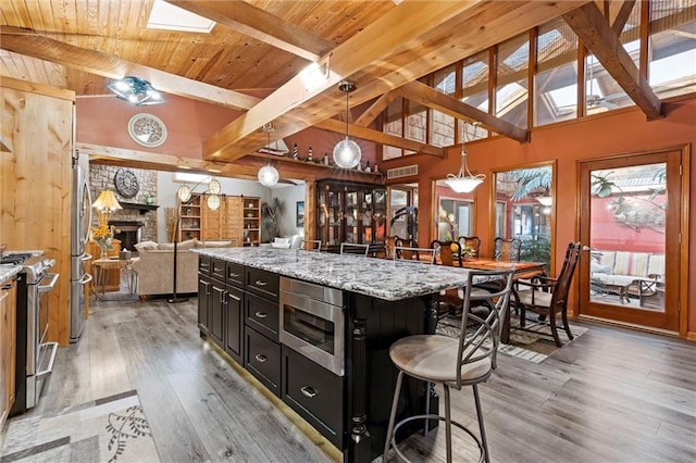 kitchen featuring dark cabinets, a breakfast bar, a skylight, wood ceiling, and appliances with stainless steel finishes