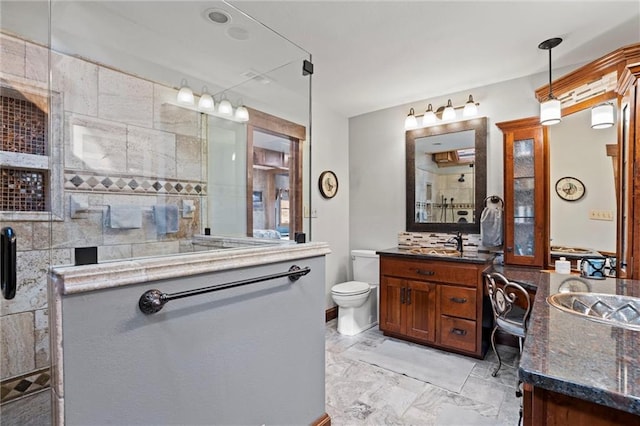 full bath with toilet, marble finish floor, a tile shower, and vanity