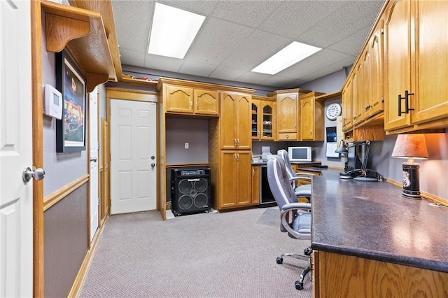 office space featuring a paneled ceiling, built in study area, and baseboards