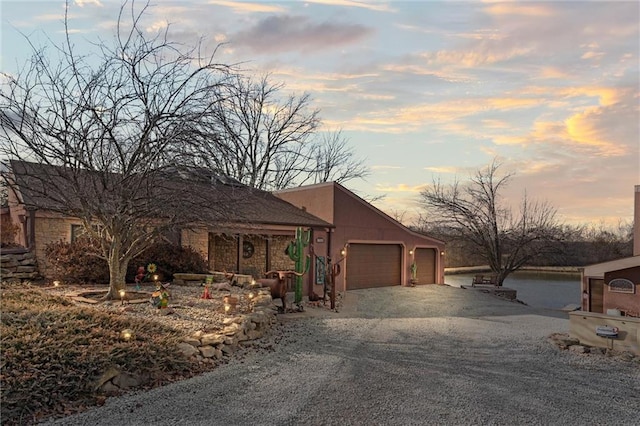 view of front of property featuring a garage, stucco siding, and gravel driveway