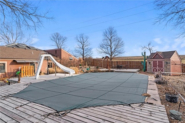 view of pool featuring an outbuilding, a storage unit, a patio area, a water slide, and a fenced backyard