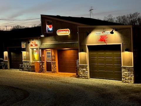 exterior space featuring a garage, stone siding, and driveway