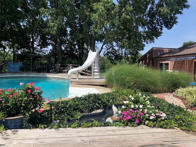 pool with a water slide and a wooden deck