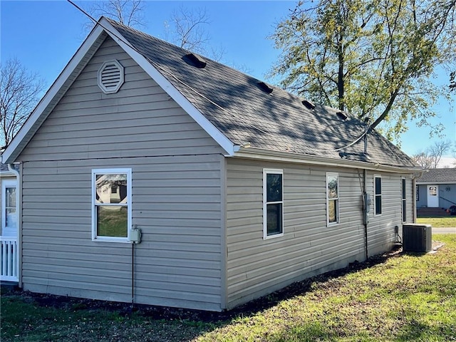 view of property exterior featuring roof with shingles, a lawn, and central AC unit