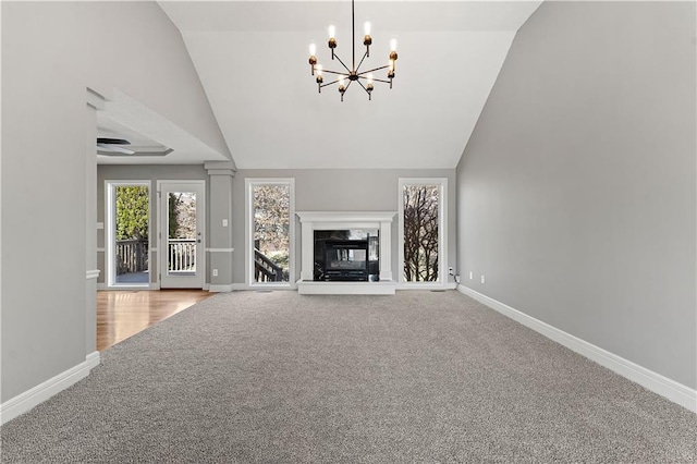 unfurnished living room featuring baseboards, a chandelier, lofted ceiling, a premium fireplace, and carpet floors