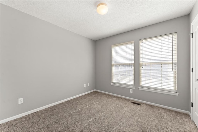 spare room featuring baseboards, visible vents, a textured ceiling, and carpet