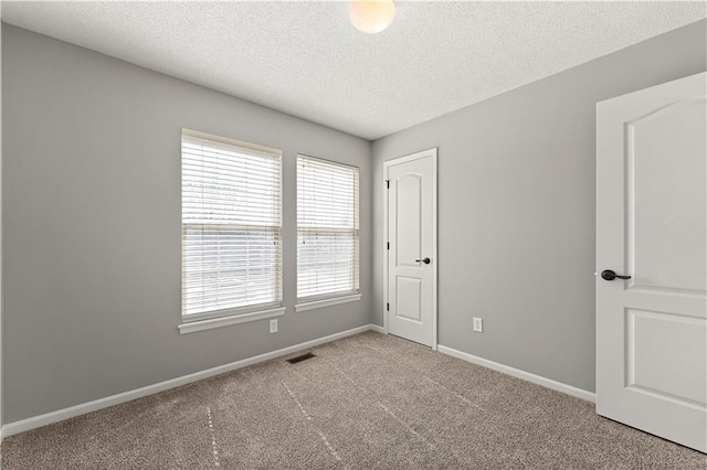 unfurnished bedroom featuring baseboards, visible vents, carpet floors, and a textured ceiling