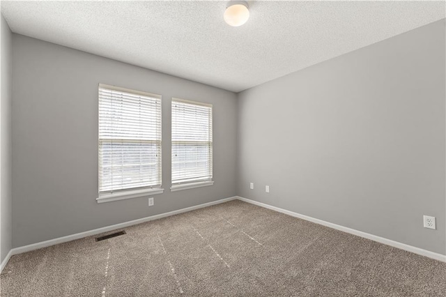 carpeted empty room featuring visible vents, a textured ceiling, and baseboards