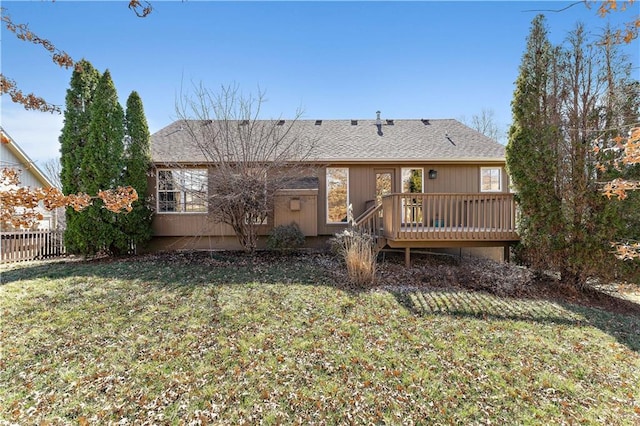 back of property featuring a lawn, roof with shingles, a deck, and fence