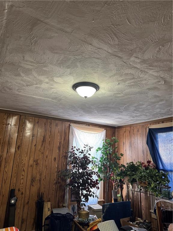 interior space with a textured ceiling and wooden walls