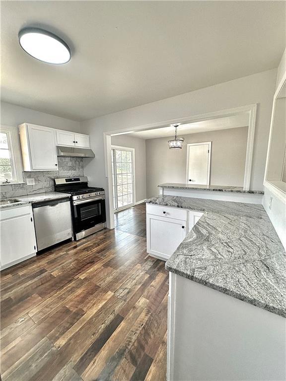 kitchen featuring stainless steel appliances, dark wood-style flooring, white cabinetry, and a healthy amount of sunlight