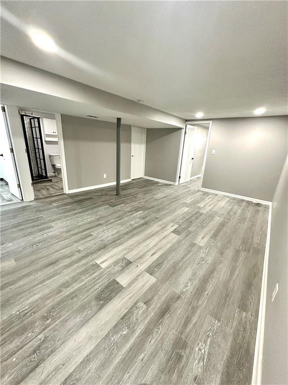 finished basement featuring a textured ceiling, wood finished floors, and baseboards