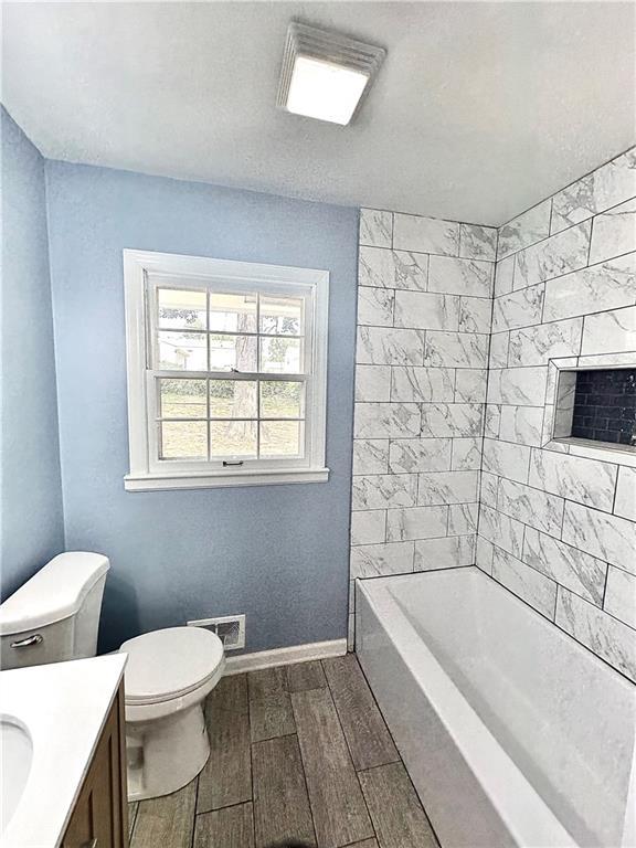 full bathroom with baseboards, visible vents, toilet, vanity, and wood finish floors