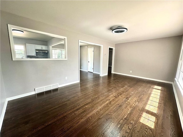 spare room featuring baseboards, visible vents, and dark wood finished floors