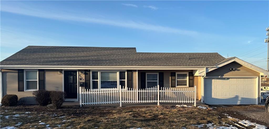 ranch-style house featuring a porch, roof with shingles, and an attached garage