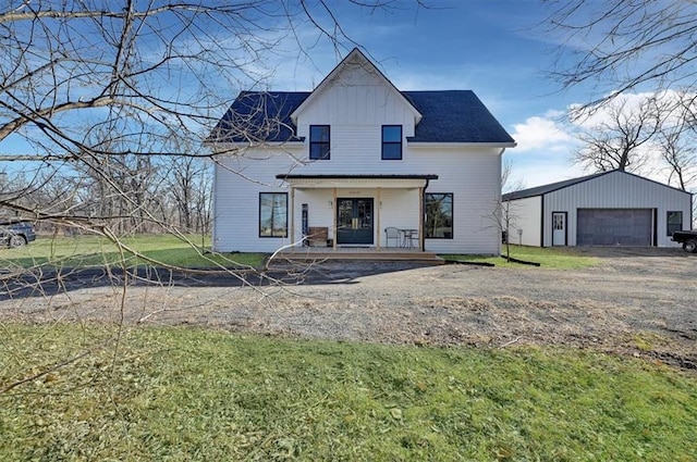 modern farmhouse with a porch, a detached garage, an outdoor structure, a front lawn, and board and batten siding